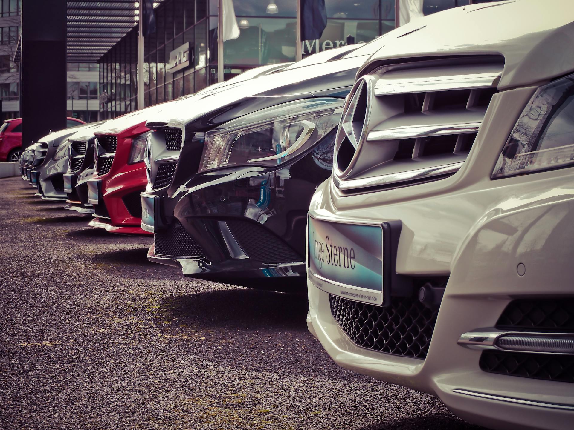 Row of vehicles lined up at an outdoor dealership lot under an open sky